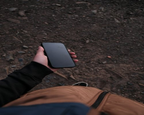 A relaxed person holding a clean smartphone at a proper viewing distance outdoors